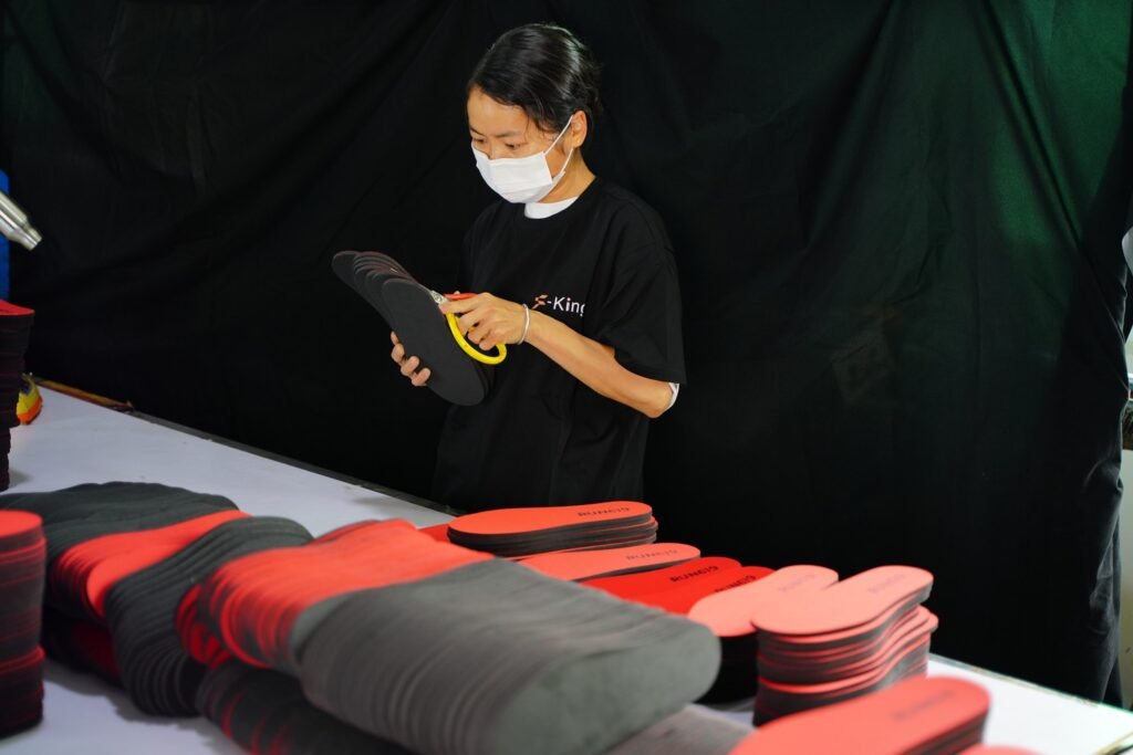 Worker performing quality inspection on custom shoe insoles, checking product structure and finish before packaging for OEM and ODM orders.