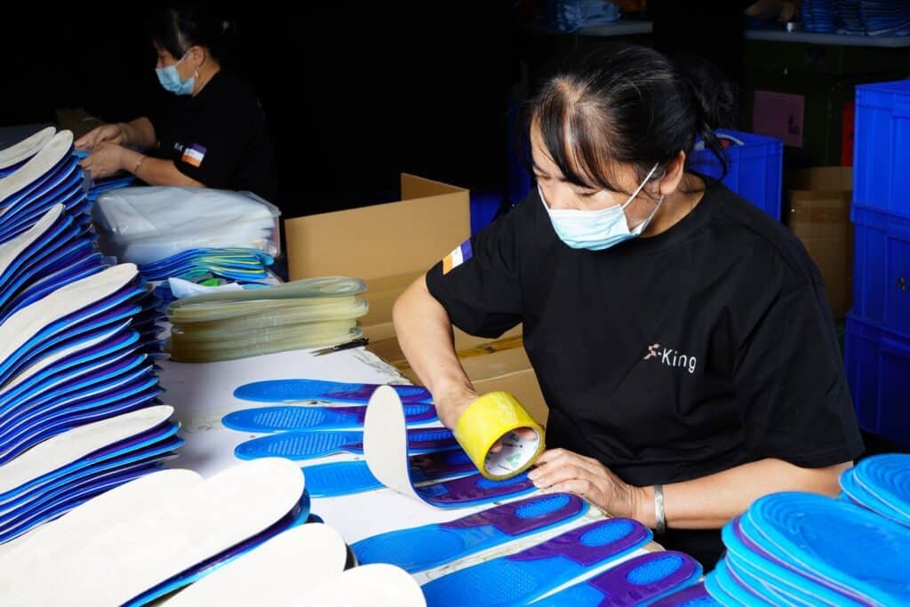 Workers performing quality inspection on shoe insoles during the manufacturing process
